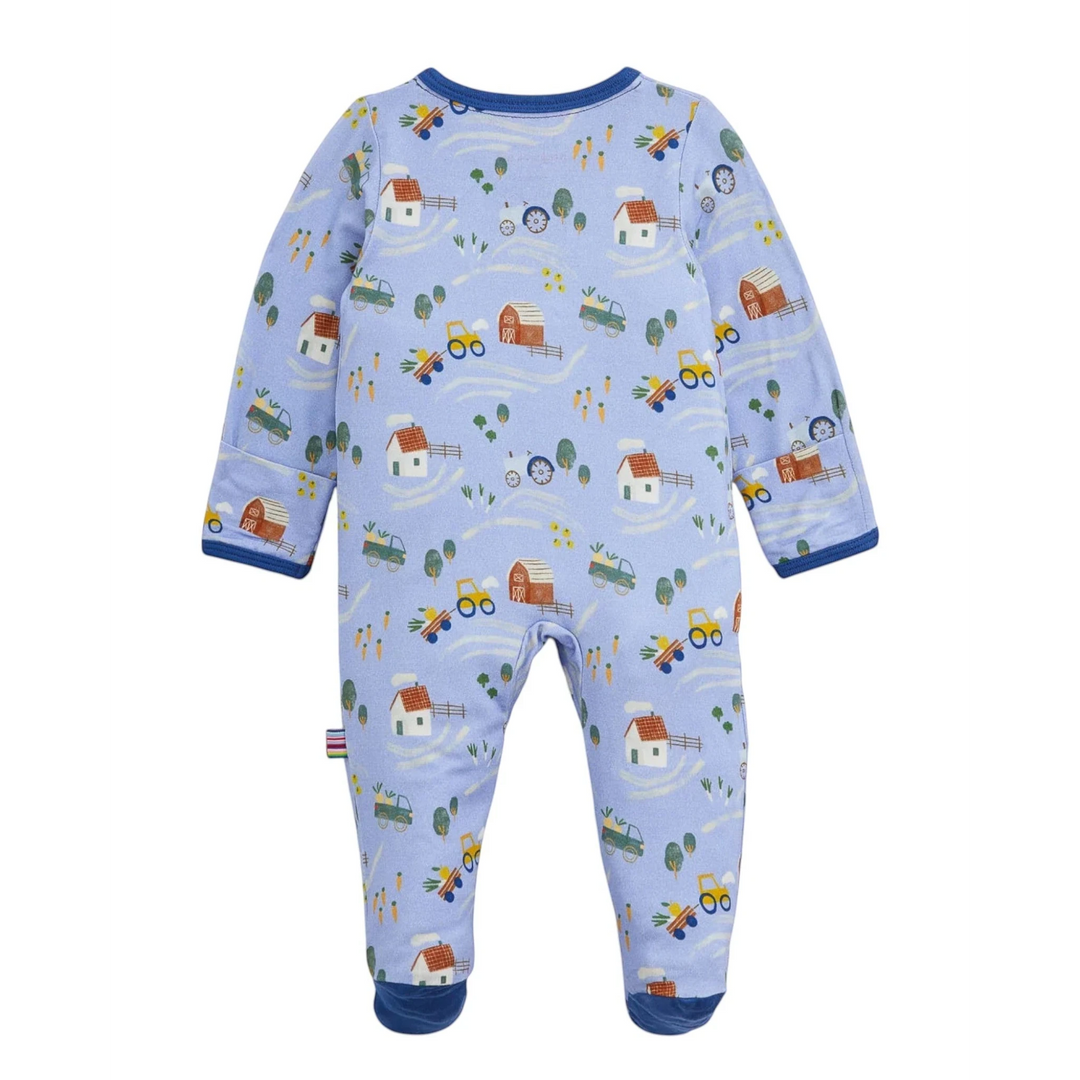 That Store baby footie in light blue modal with a farm-themed print featuring barns, tractors, and carrots.