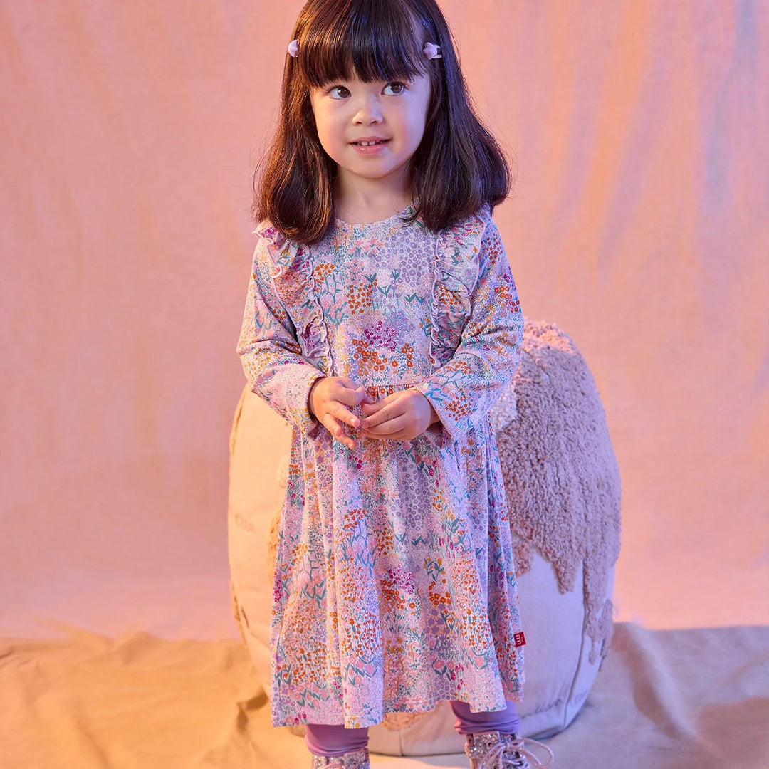 A young girl wearing a That Store floral print modal dress and leggings set with magnetic closures.