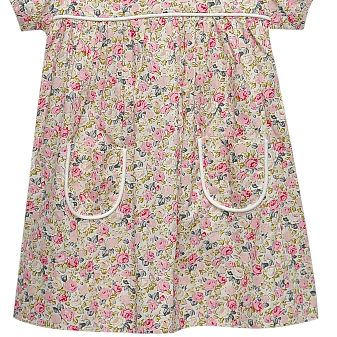 That Store Floral Pink Rose Reagan dress featuring a delicate pink rose print and two front pockets with white trim.