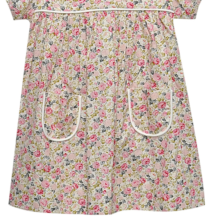 That Store Floral Pink Rose Reagan dress featuring a delicate pink rose print and two front pockets with white trim.
