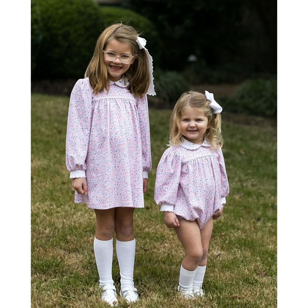 Two girls wearing That Store long sleeve floral dresses with pumpkin embroidery on collars in a grassy outdoor setting.