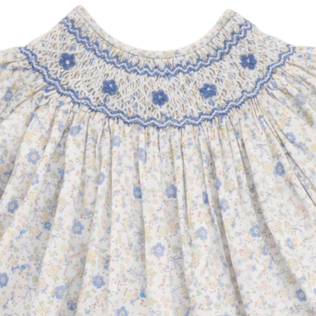 That Store girls cotton dress featuring blue and yellow floral bow print with intricate blue chest smocking detail.