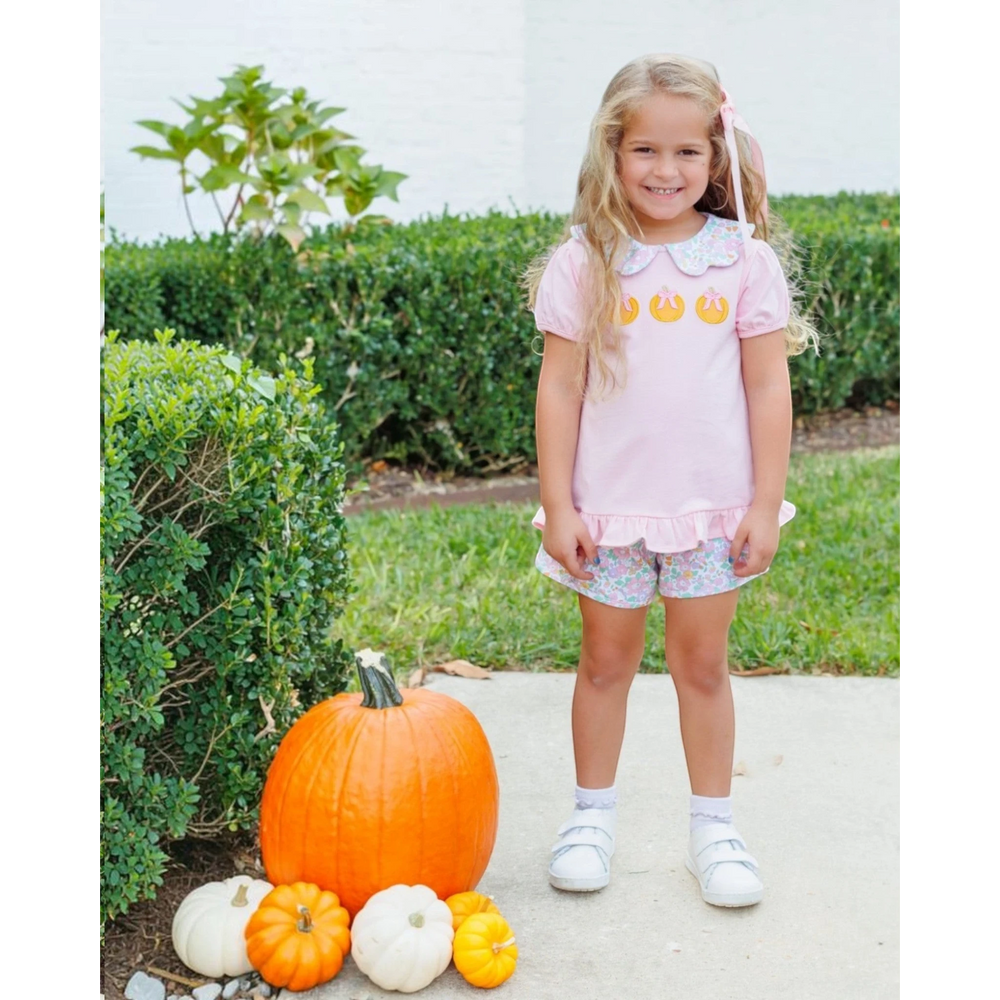 That Store girl wearing a pink cotton short set with pumpkin appliques and floral shorts standing by pumpkins