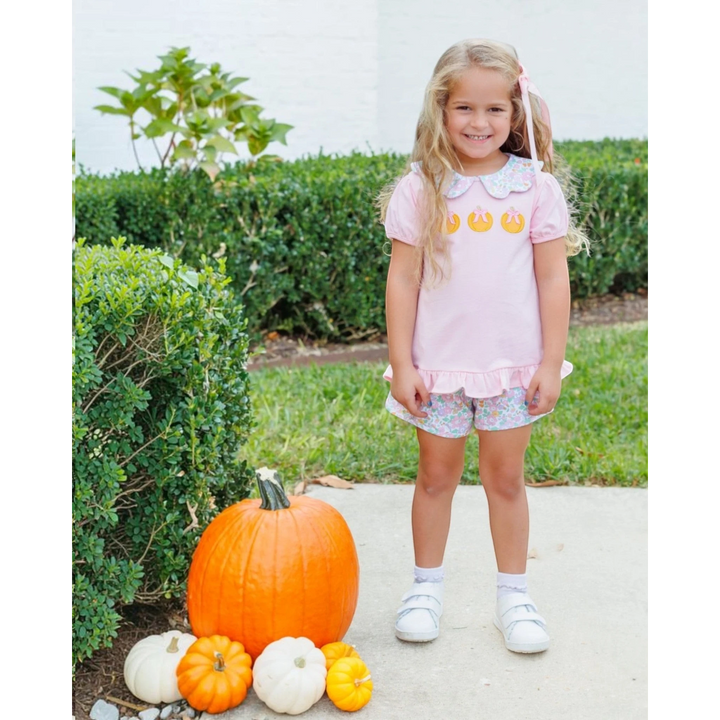 That Store girl wearing a pink cotton short set with pumpkin appliques and floral shorts standing by pumpkins