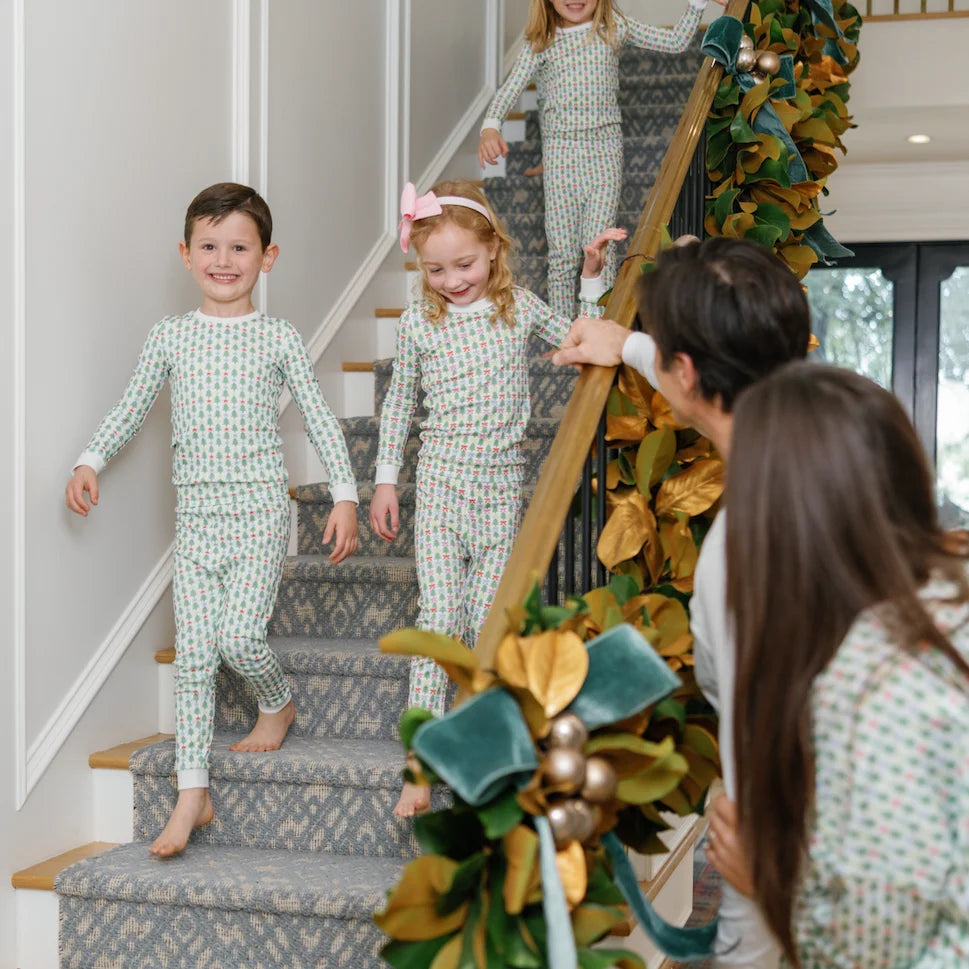 That Store Grayson pajama set with green trees and stars on children walking down a decorated holiday staircase.