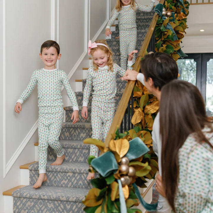 That Store Grayson pajama set with green trees and stars on children walking down a decorated holiday staircase.