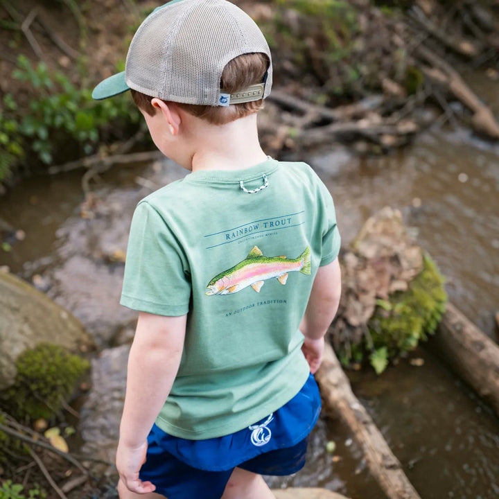 That Store kid wearing a hedge green cotton t-shirt with a rainbow trout graphic on the back while standing in a creek