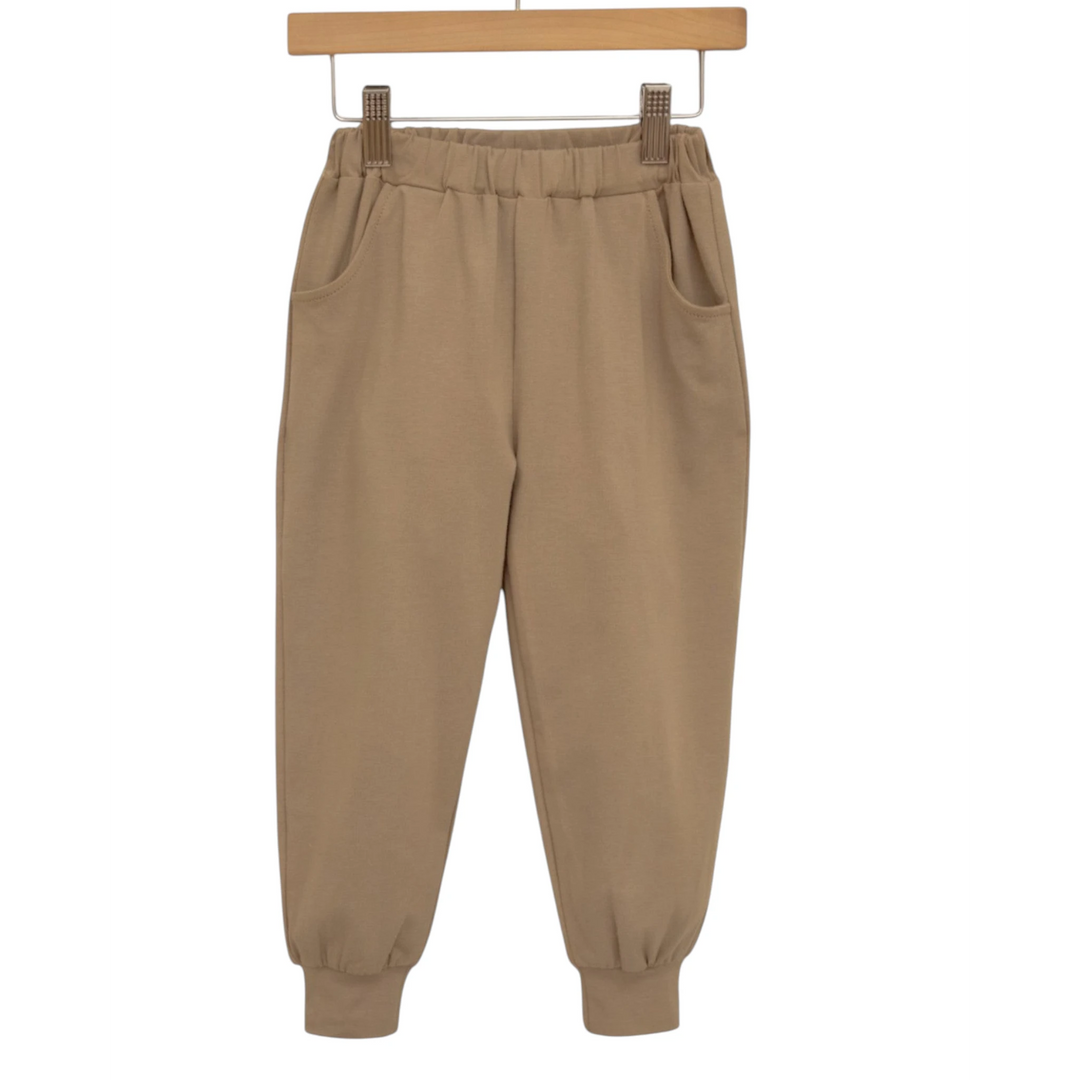 That Store khaki cotton blend joggers for boys with an elastic waistband and relaxed fit hanging on a wooden hanger