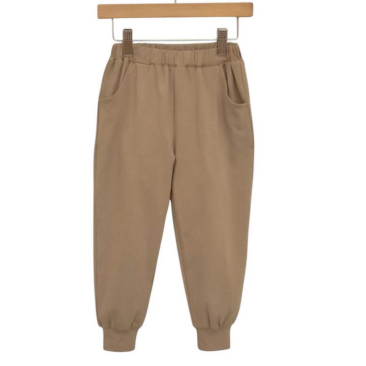 That Store khaki cotton blend joggers for boys with an elastic waistband and relaxed fit hanging on a wooden hanger