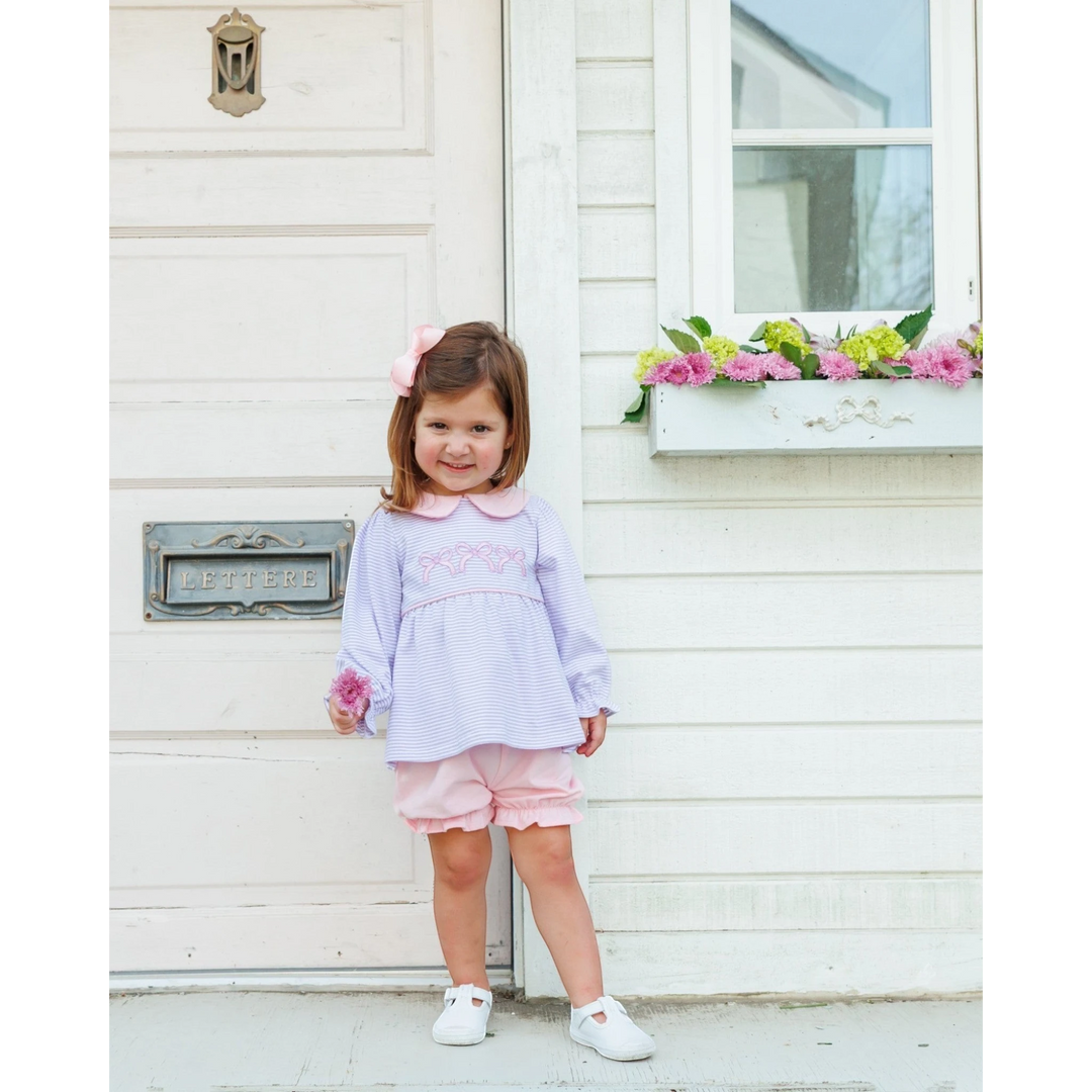 That Store lavender stripe long-sleeve top and pink bloomer set worn by a toddler girl with a matching hair bow.