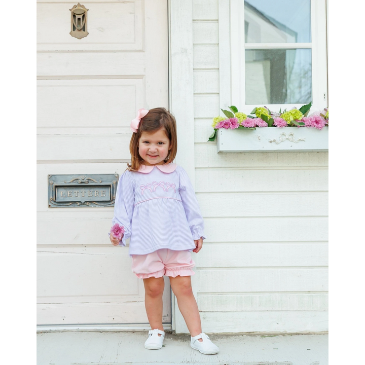 That Store lavender stripe long-sleeve top and pink bloomer set worn by a toddler girl with a matching hair bow.