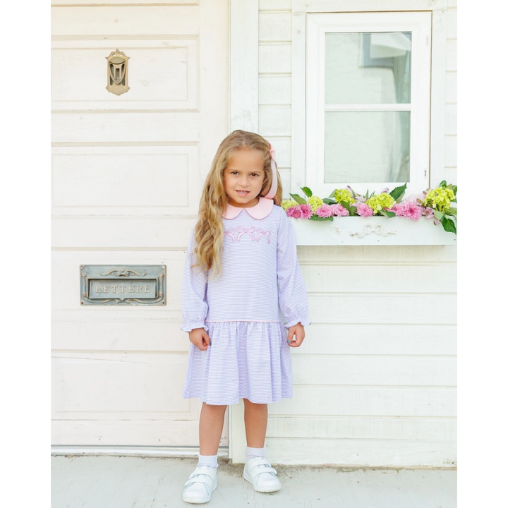 That Store lavender striped cotton dress with pink collar and bow embroidery worn by a young girl outdoors