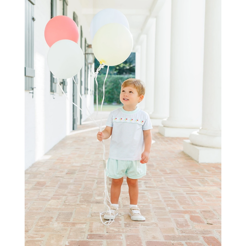 Toddler boy wearing a That Store light blue gingham short set with Mickey balloon embroidery holding colorful balloons