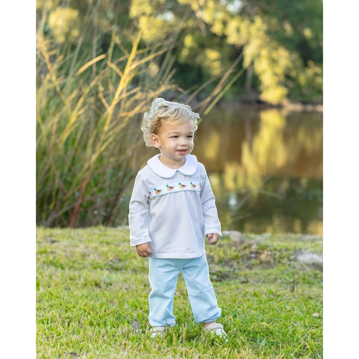 That Store toddler boy wearing a white long-sleeve top with mallard ribbon and light blue bloomer pants outdoors.