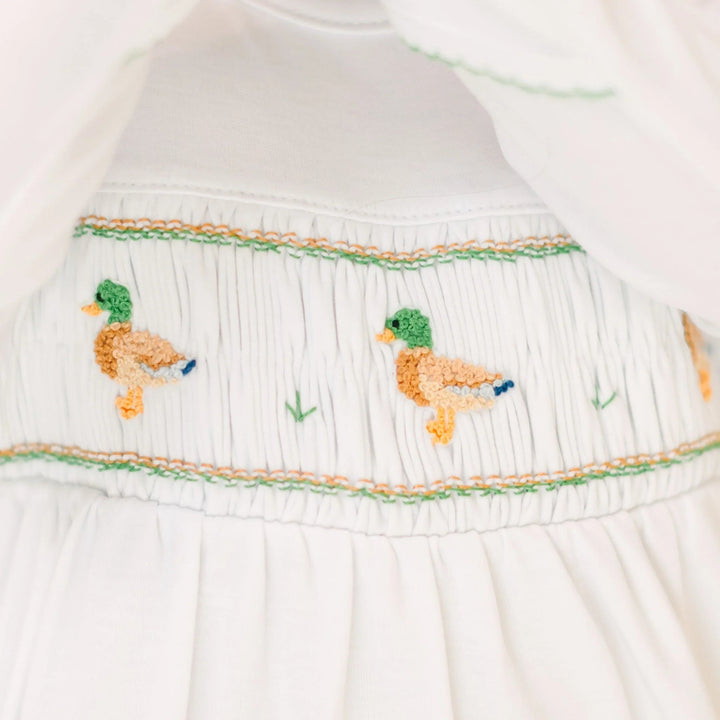 That Store boys white Pima cotton footie featuring detailed mallard duck smocking and green embroidery accents.