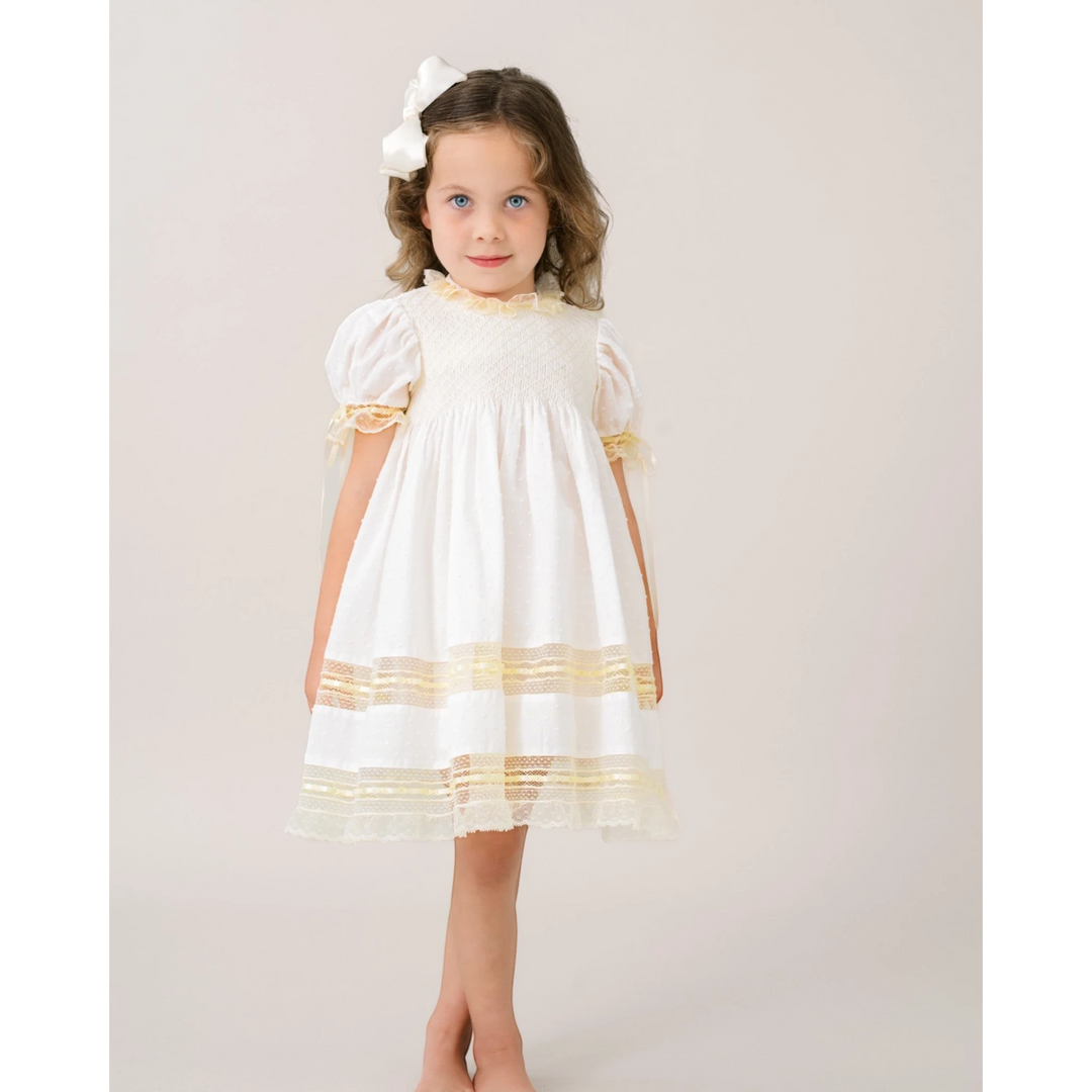 That Store Margaret white Swiss dot dress with ecru lace trim worn by a young girl with a matching hair bow