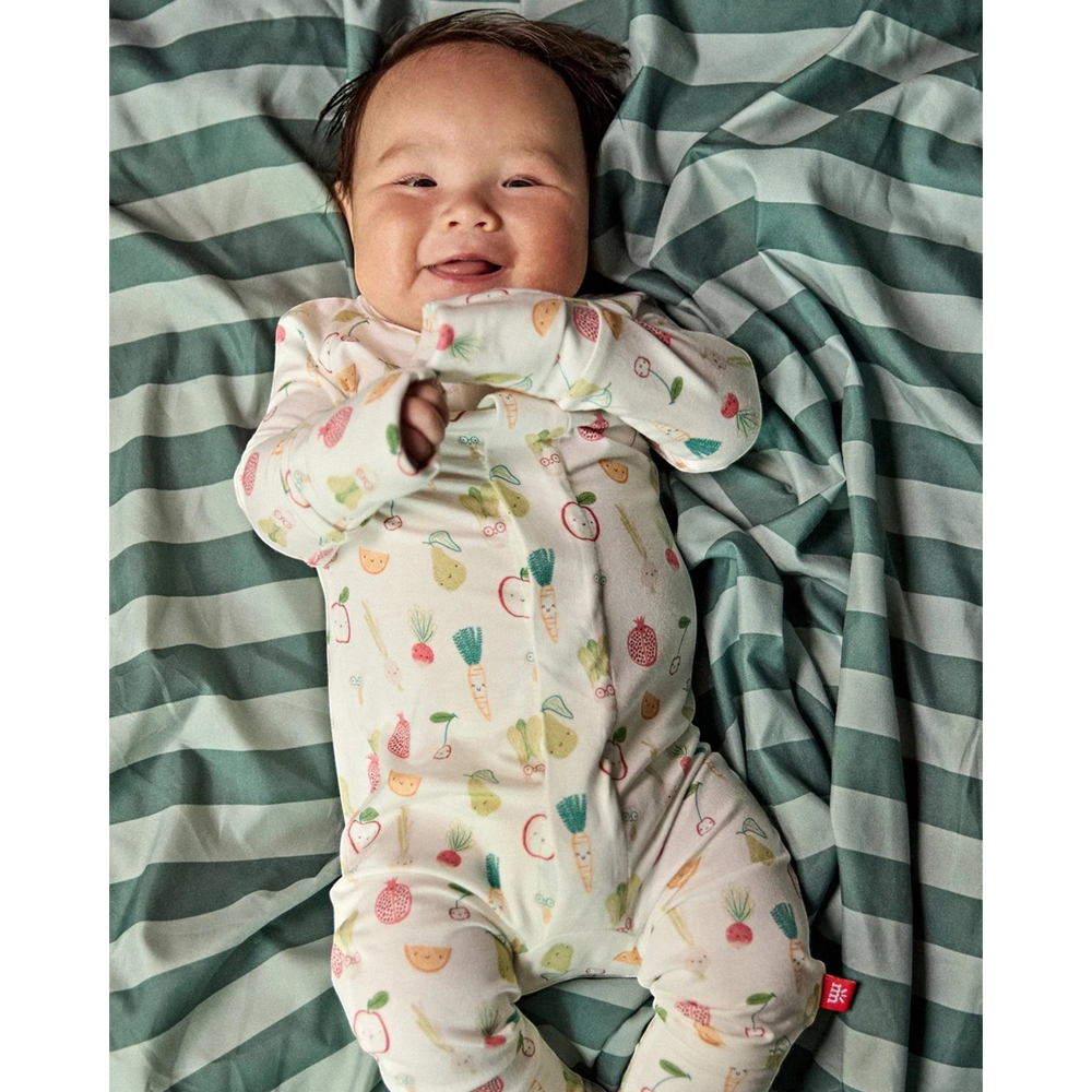 That Store baby wearing a soft modal convertible coverall with a colorful fruit and vegetable print on a striped mat