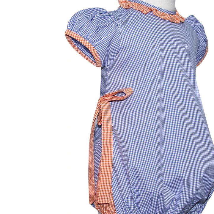 That Store navy and orange gingham bubble romper for girls with ruffled sleeves and a side tie detail.