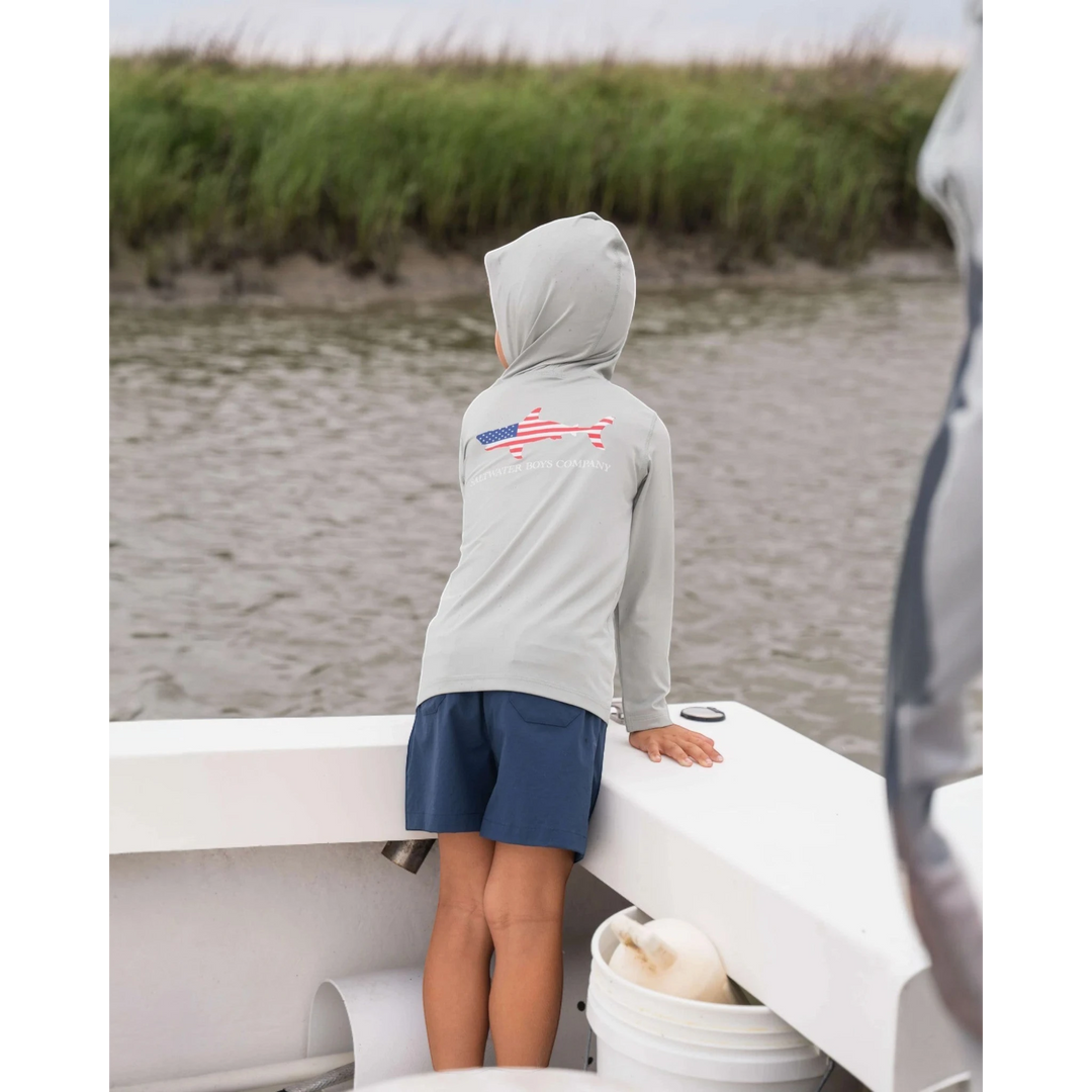 That Store navy performance shorts on a boy standing on a boat, featuring an elastic waist and moisture-wicking fabric.