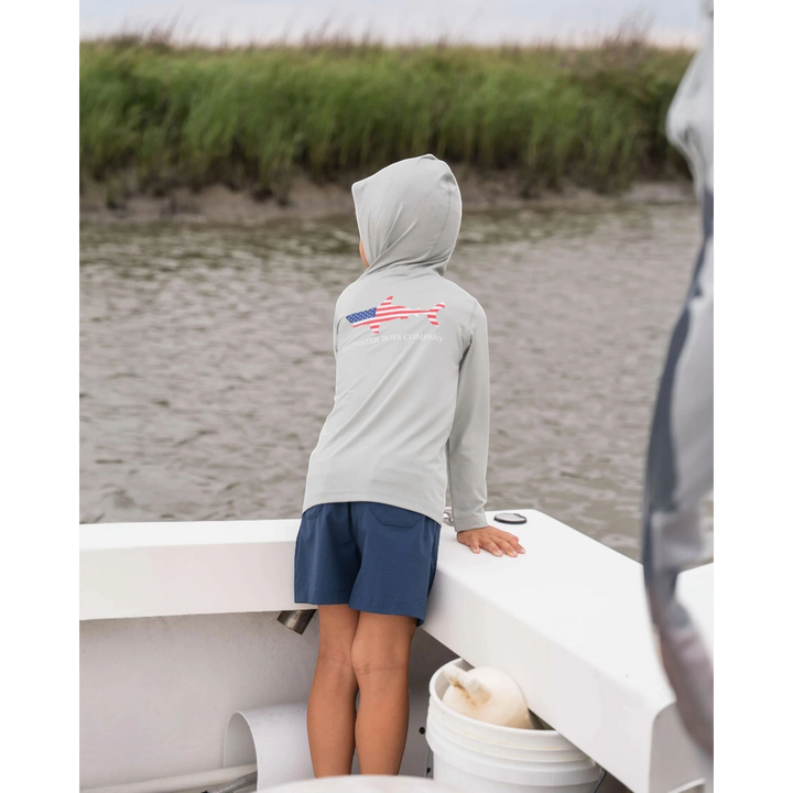 That Store navy performance shorts on a boy standing on a boat, featuring an elastic waist and moisture-wicking fabric.