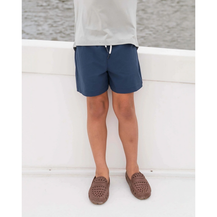 That Store navy performance shorts with elastic drawstring waist worn by a boy on a boat deck