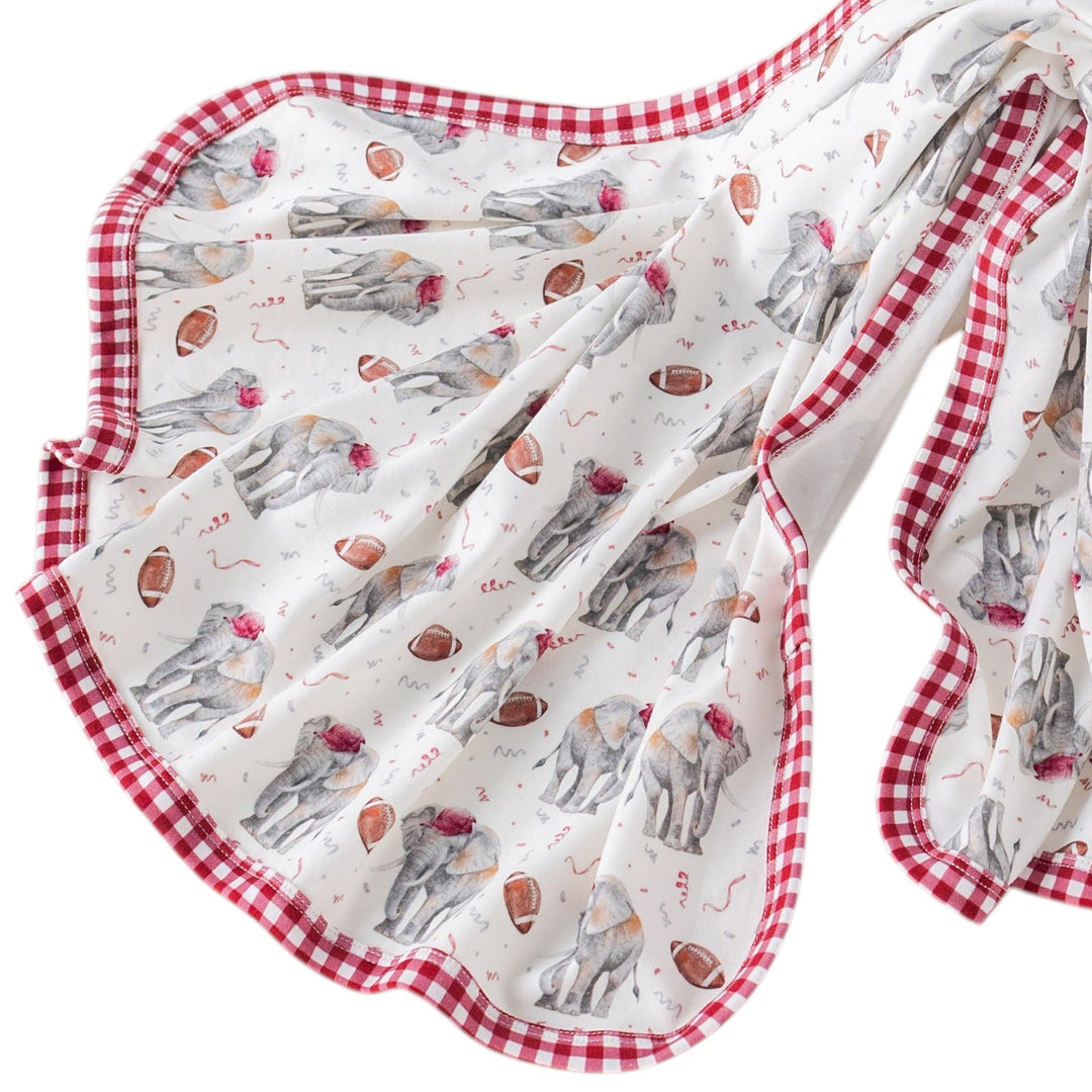 That Store organic cotton muslin swaddle blanket featuring elephant and football print with red gingham trim.