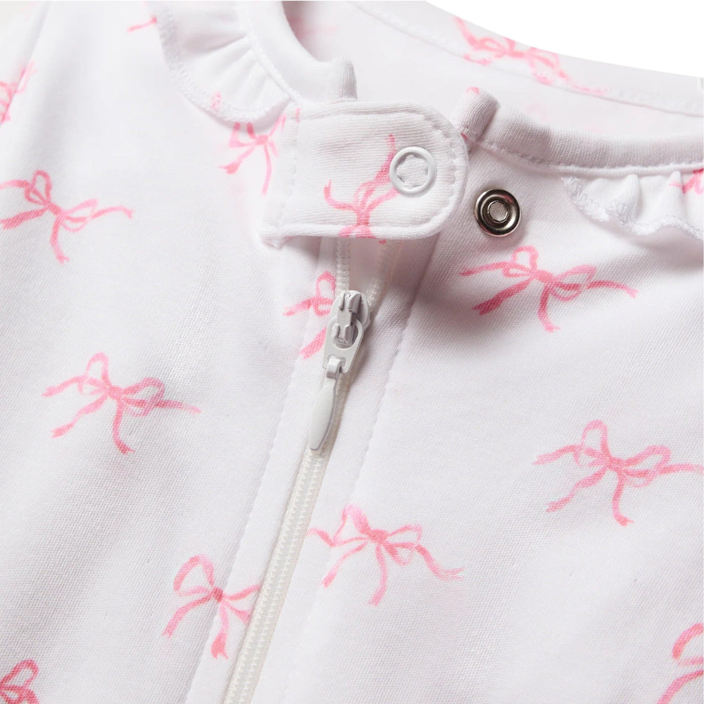 That Store baby romper in white Pima cotton with pink bow print, featuring a ruffle collar and front zipper closure.