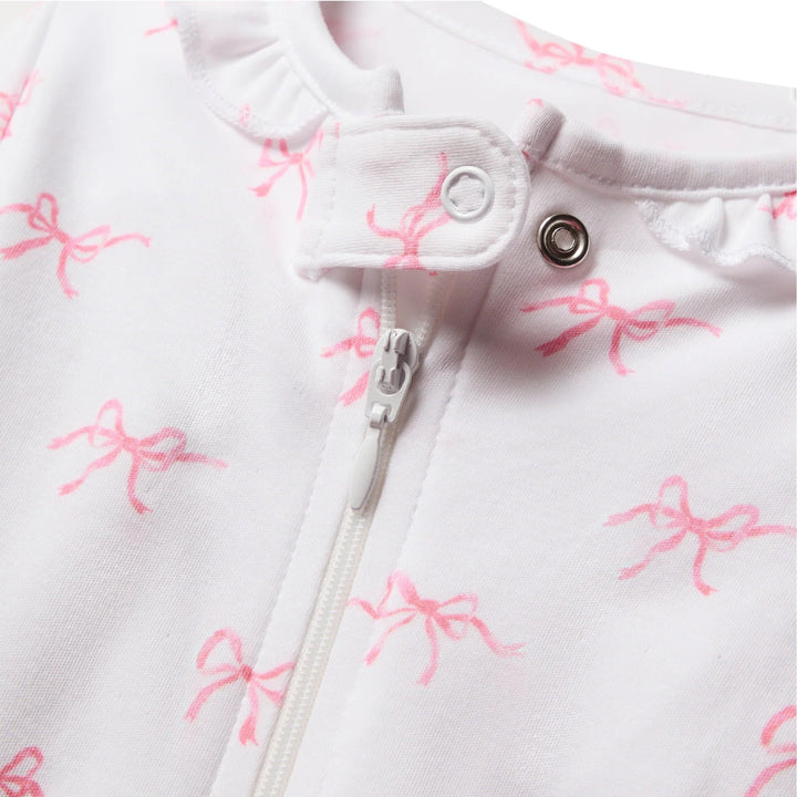 That Store baby romper in white Pima cotton with pink bow print, featuring a ruffle collar and front zipper closure.