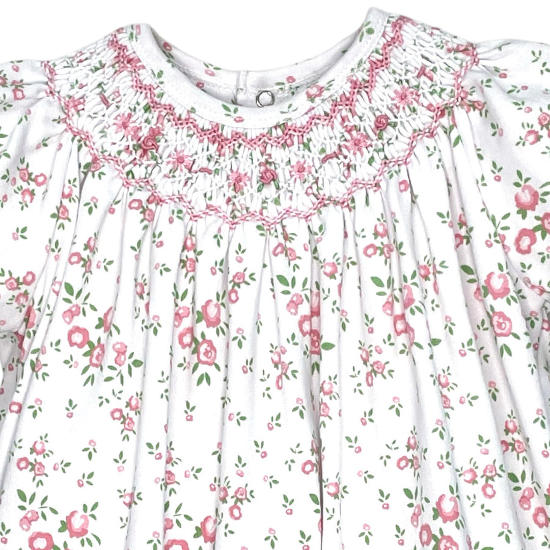 That Store girls pink floral knit romper featuring intricate hand-stitched smocking and delicate puff sleeves.
