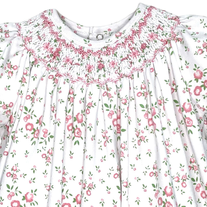 That Store girls pink floral knit romper featuring intricate hand-stitched smocking and delicate puff sleeves.