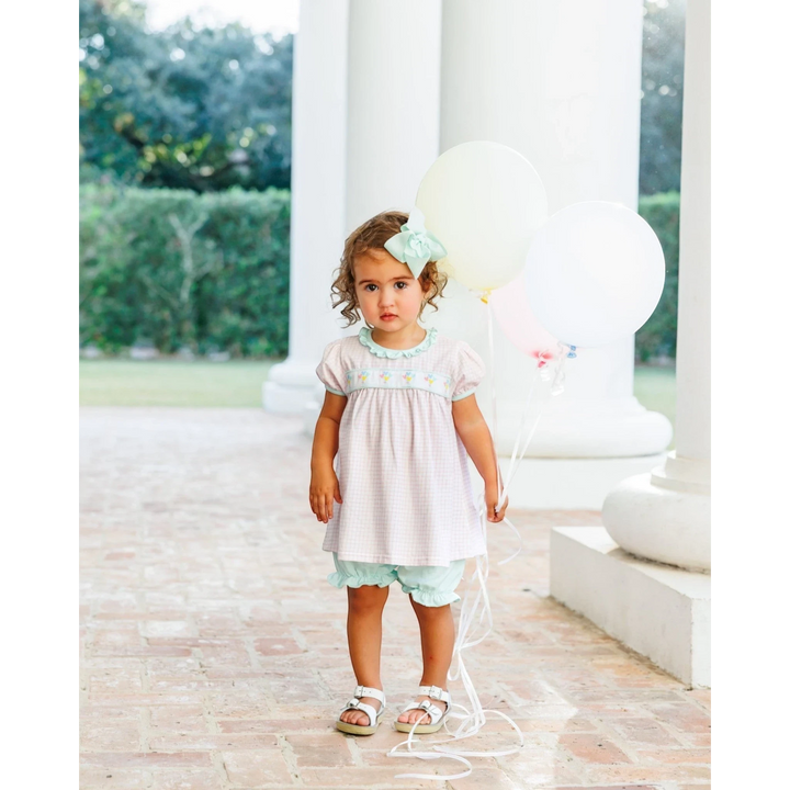 Toddler girl wearing a That Store pink gingham bloomer set with balloon embroidery, ribbon accents, and a hair bow.