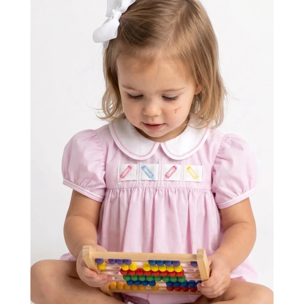 That Store toddler girl wearing a pink mini gingham bubble dress with interchangeable crayon ribbon detail
