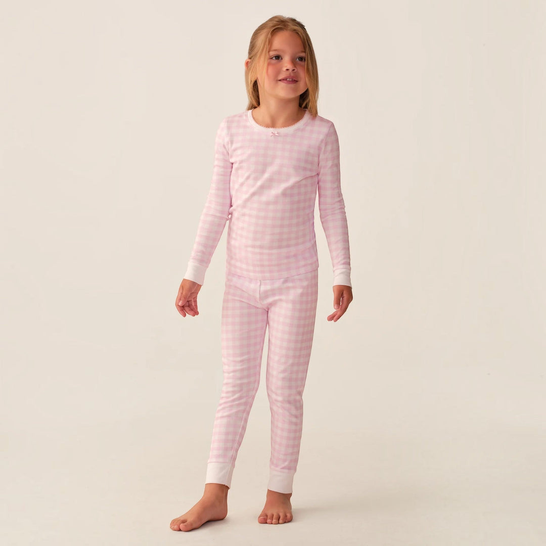 Young girl wearing a That Store pink gingham long sleeve Pima cotton pajama set with a small bow detail