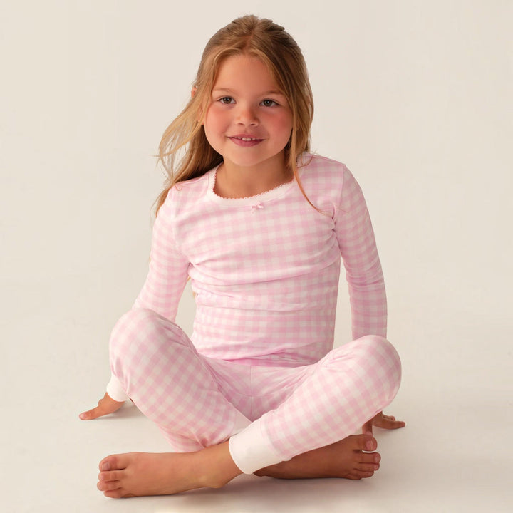Young girl wearing a That Store pink gingham long sleeve Pima cotton pajama set with a snug fit on a white background
