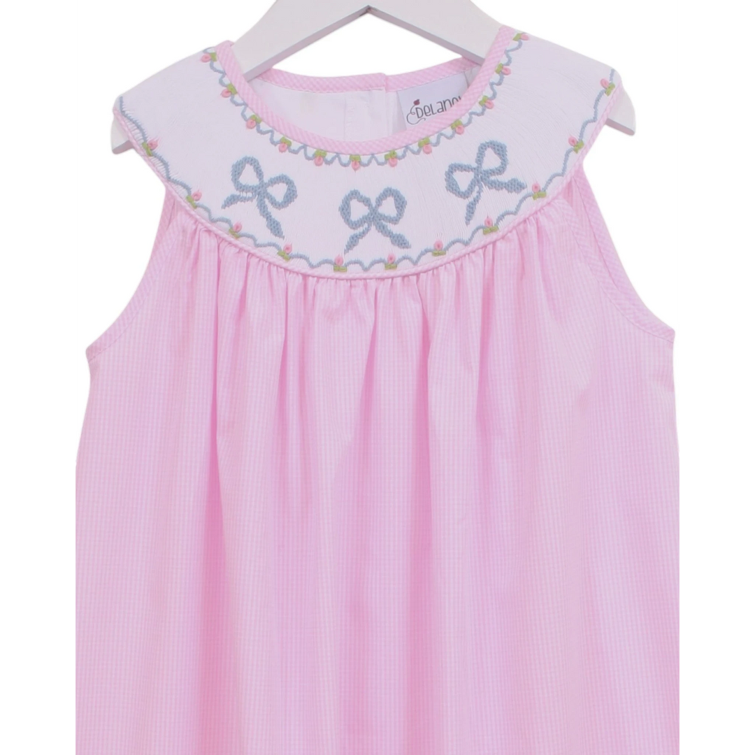 That Store pink gingham sleeveless dress with a white smocked yoke featuring embroidered blue bows and floral detail.