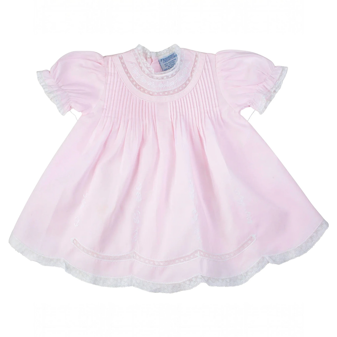 That Store pink baby slip dress with lace trim, floral embroidery, and pintuck details on a polyester cotton blend.
