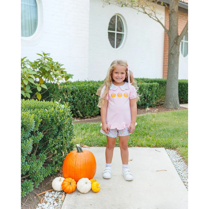 That Store pink short set with pumpkin appliques and floral trim worn by a girl outdoors with pumpkins