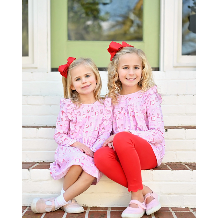 Two girls wearing That Store pink Letters to Santa swing tops and red knit leggings with matching red hair bows
