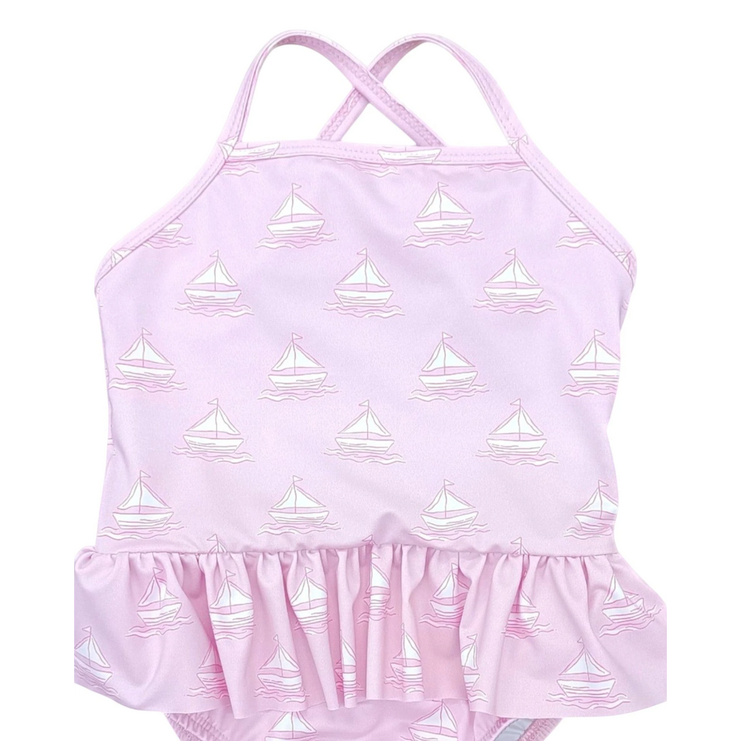 That Store girls pink one-piece swimsuit with white sailboat print and ruffled skirt detail and crisscross straps.