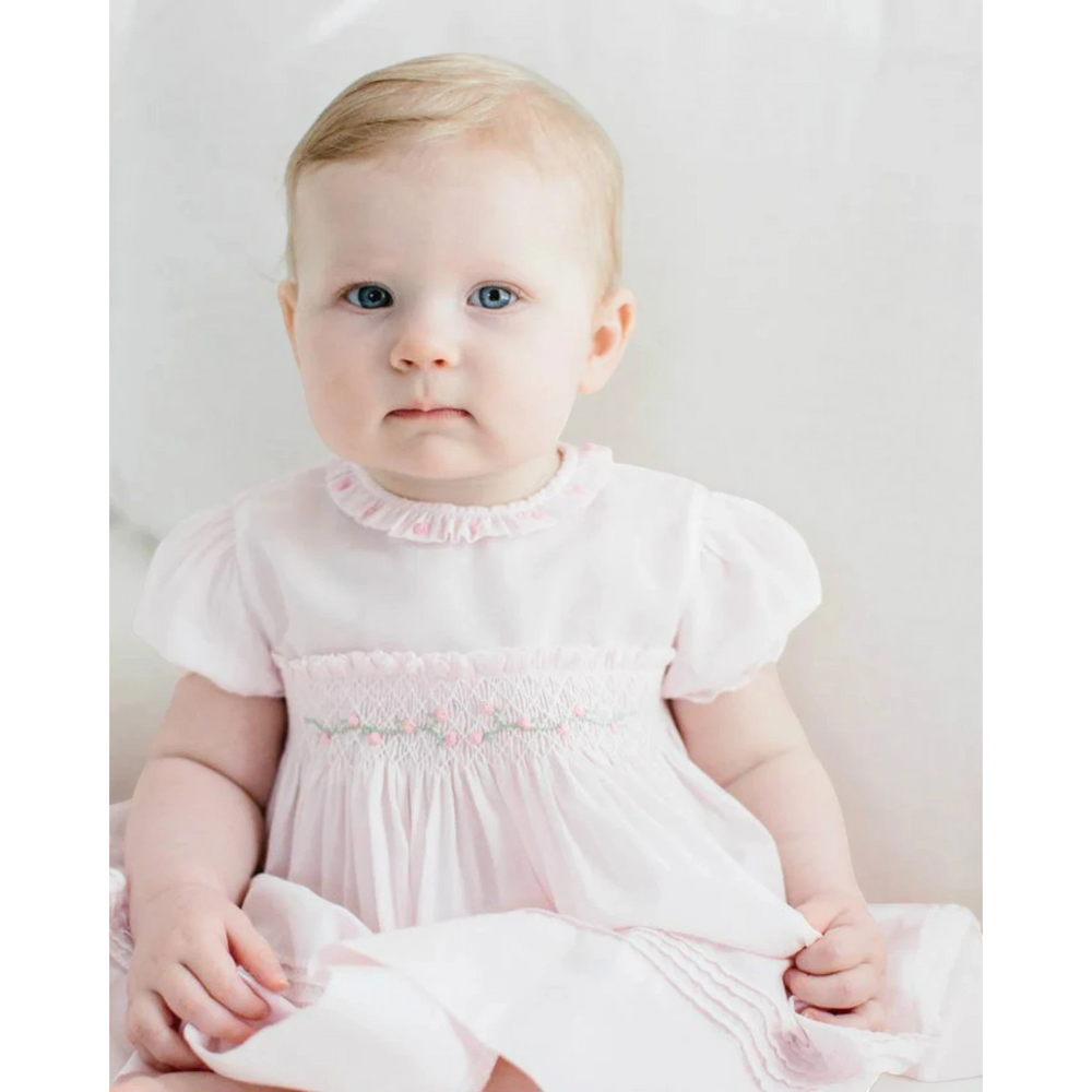 That Store pink baby dress with hand-smocked rosebud bodice, ruffled collar, and pintuck hem details.