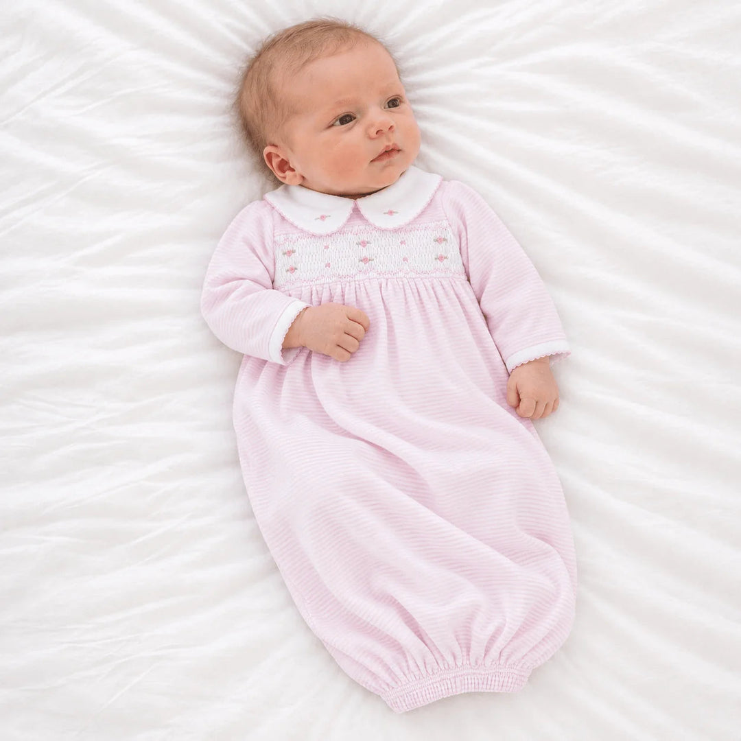 Baby wearing a That Store pink micro-stripe Pima cotton gown with hand-smocked bodice, rosebuds, and Peter Pan collar.