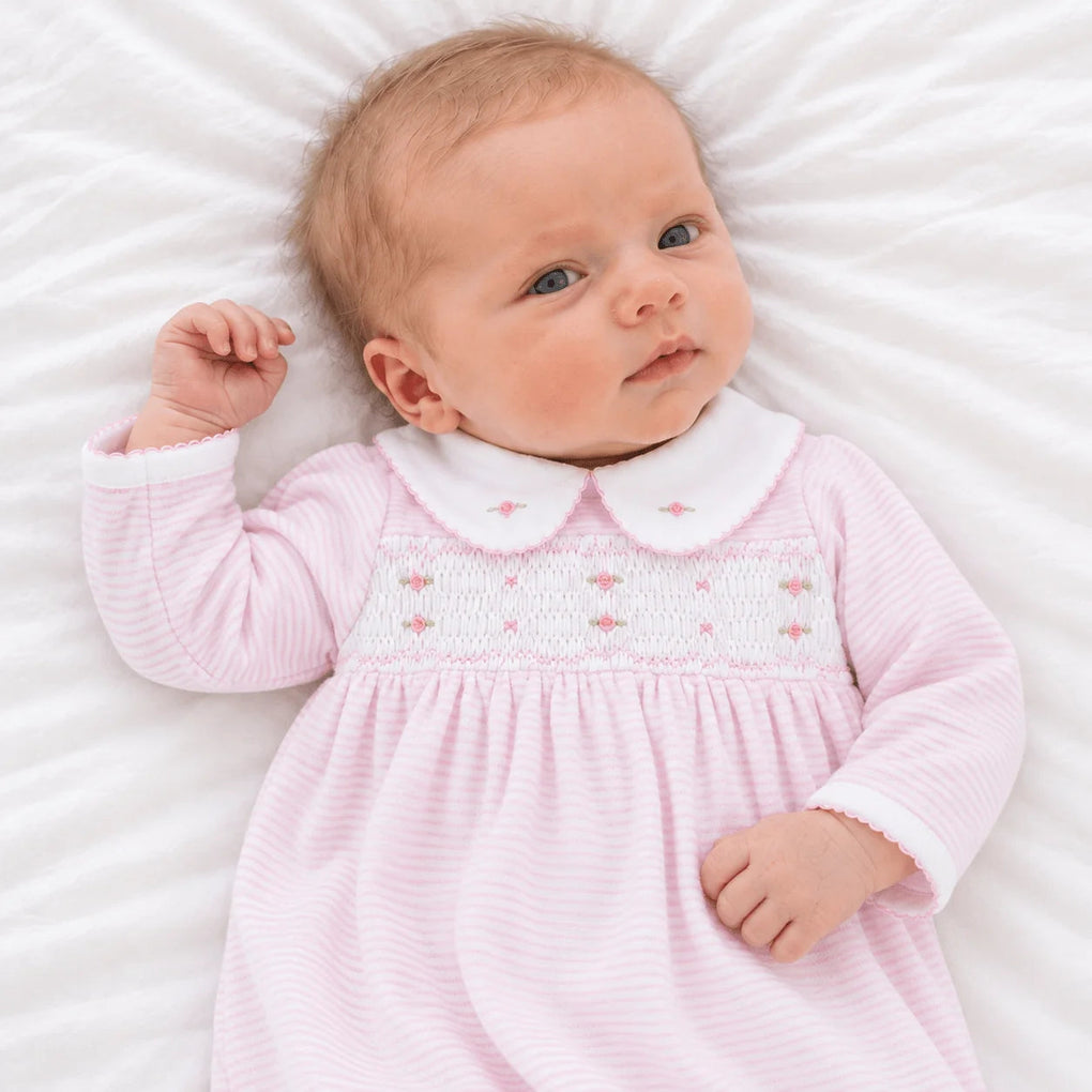 Baby wearing a That Store pink micro-stripe smocked gown with a Peter Pan collar and embroidered rosebuds.