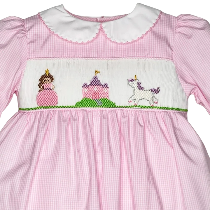 That Store pink gingham dress with hand-smocked fairytale scene featuring a princess, castle, and unicorn.