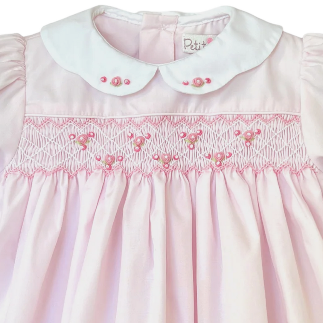 That Store girls pink dress with corded smocking, embroidered rosette details, and a white scalloped collar.