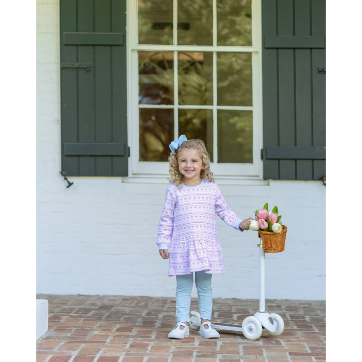 Young girl wearing a That Store sweetheart French terry tunic set with a pink bow pattern and light blue leggings.