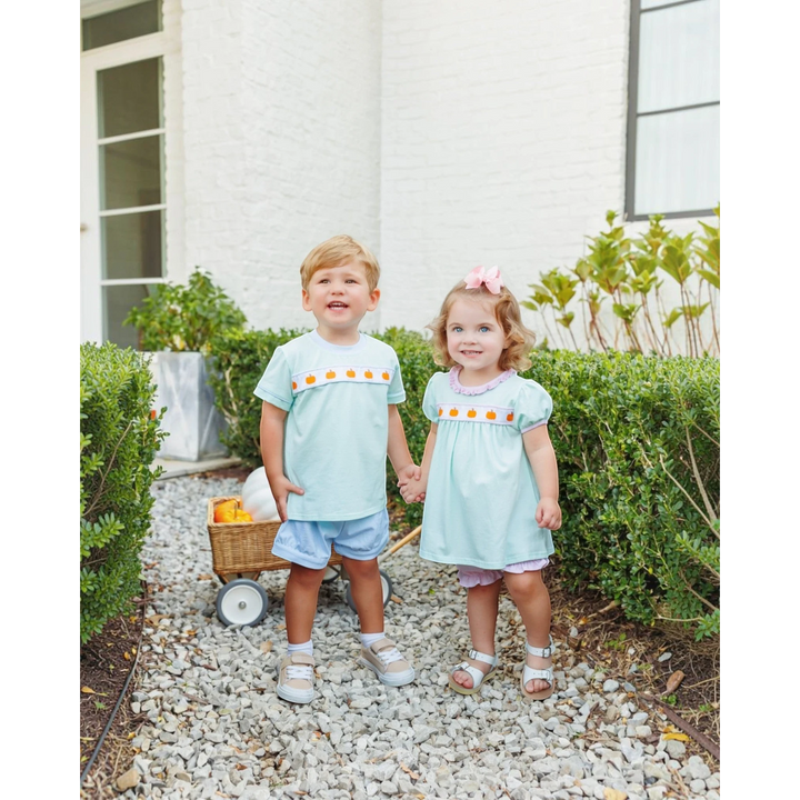 That Store Pumpkin Rowe mint and pink cotton bloomer set worn by a young girl standing next to a boy outdoors.