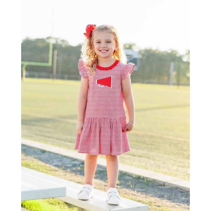 That Store red and white striped dress with megaphone applique worn by a smiling girl on a sports field