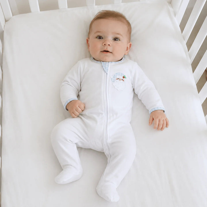 Baby wearing a That Store white Pima cotton zip footie with a festive Santa appliqué and light blue gingham trim.