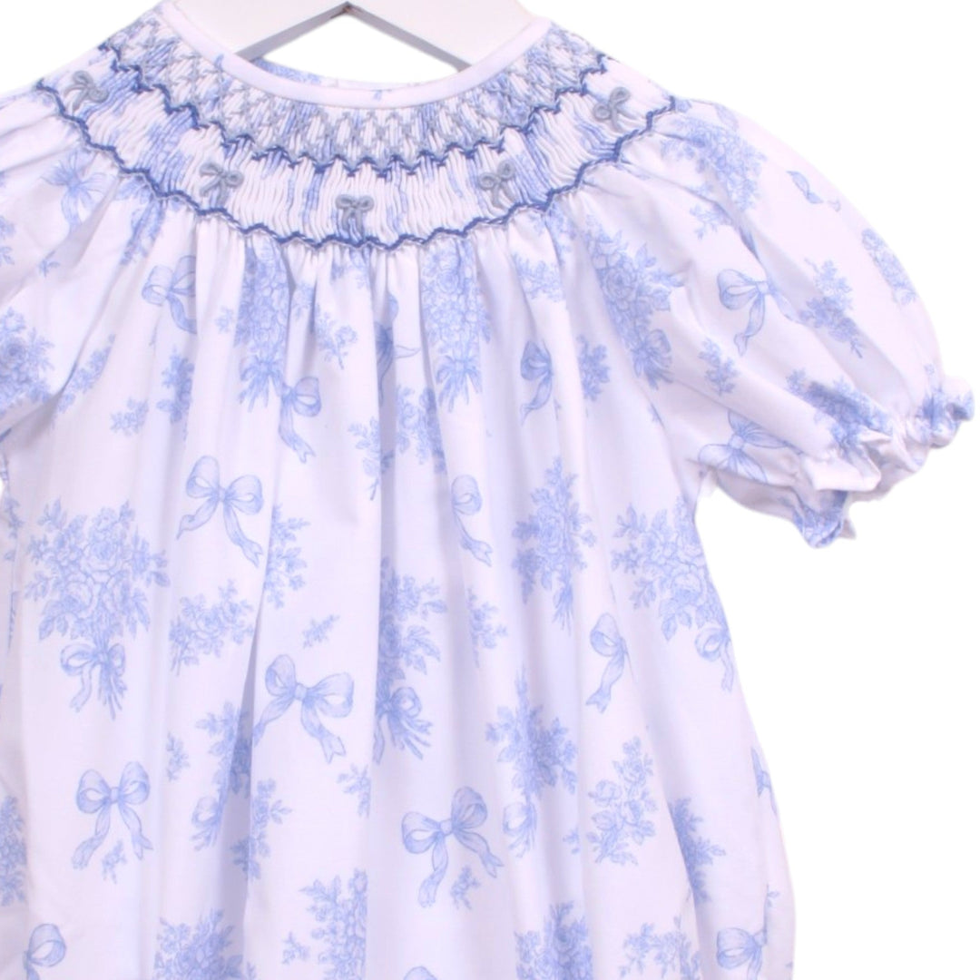 That Store girls bubble featuring a blue and white floral print with intricate smocking and bows at the neckline.