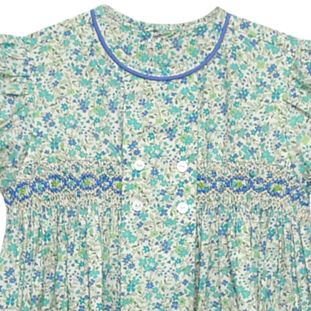 That Store Ava Rose dress with blue and green floral print, smocked bodice, puff sleeves, and blue piping detail.